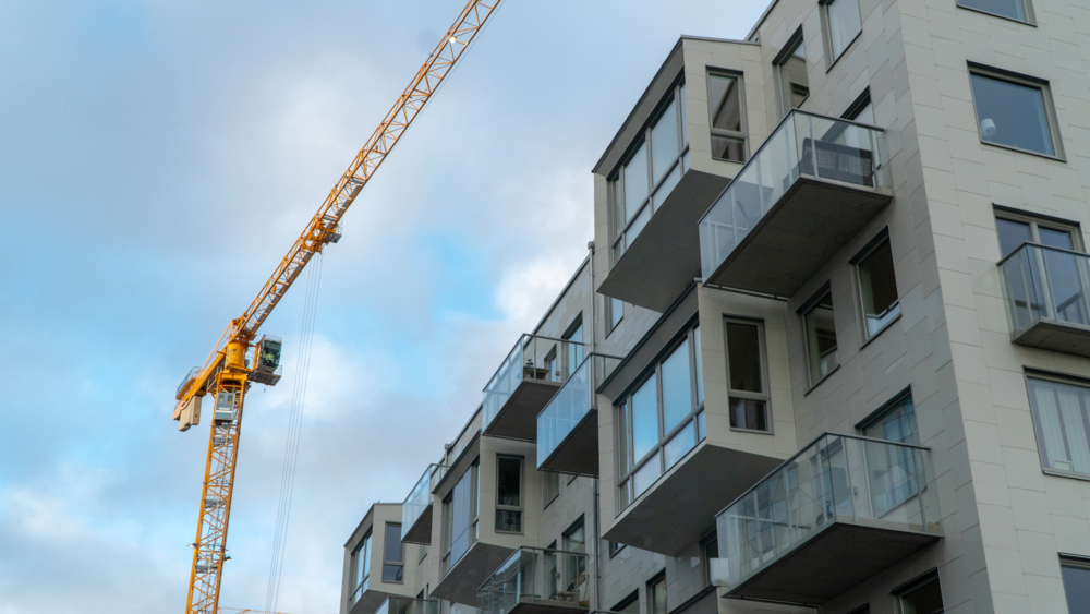 Byggkran vid fastighet i Lindholmshamnen en solig dag.